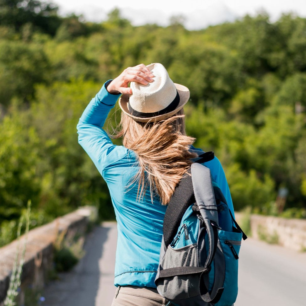 Vista trasera de un viajero con estilo, con sombrero y mochila